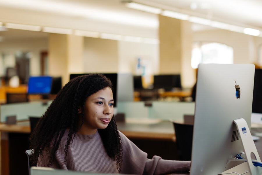 graphic arts and graphic design student uses a computer in the library.